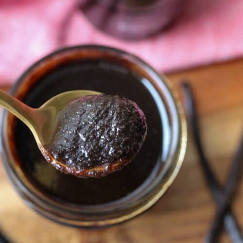 Spoon scooping vanilla bean paste out of jar.